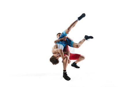 Foto de Jóvenes atletas masculinos compiten en un combate de lucha libre, mostrando habilidad y estrategia en la sesión de entrenamiento, aislados sobre fondo blanco. Concepto de deporte de combate, artes marciales, competición, torneo - Imagen libre de derechos