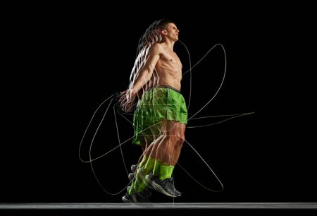 Photo for Intensity of a training session. Dynamic energy of muscular man training shirtless, jumping rope on black background with stroboscope effect. Concept of sport, active and healthy lifestyle, endurance - Royalty Free Image