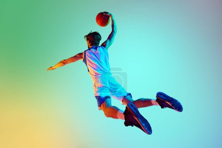 Foto de Hombre competitivo, atleta en movimiento, entrenamiento, jugar baloncesto contra el fondo gradiente en luz de neón. Concepto de deporte, competición, estilo de vida activo y saludable, juego - Imagen libre de derechos