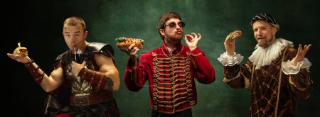 Mittelalterliche Menschen in historischen Gewändern essen gerne Burger und Hot Dogs vor texturiertem grünen Hintergrund. Konzept des Vergleichs von Epochen, Retro und Vintage, Geschichte. Kreative Collage