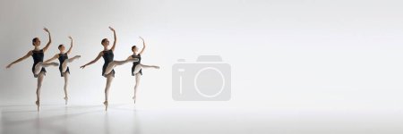 Foto de Cuatro bailarinas de ballet, chicas adolescentes en leotardos negros bailando sobre fondo gris del estudio. Sincronización. Ballet, arte, estudio de danza, estilo clásico, concepto juvenil. Banner. Espacio vacío para insertar texto - Imagen libre de derechos