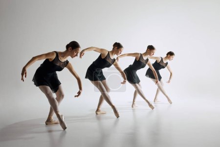 Téléchargez les photos : Quatre jeunes filles, danseuses de ballet en formation de justaucorps noirs, montrant flexibilité et chorégraphie synchronisée sur fond de studio gris. Concept d'art ballet, studio de danse, style classique, jeunesse - en image libre de droit