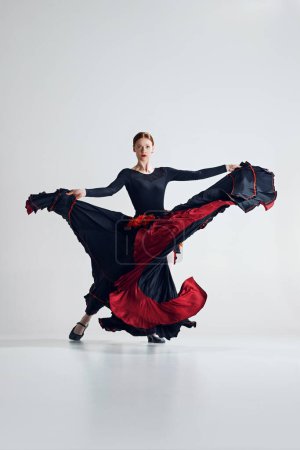Téléchargez les photos : L'essence passionnée de la danse flamenco. Femme artistique exécutant pose dynamique dansant sur fond de studio gris. Concept d'art du mouvement, danse classique, beauté, festival - en image libre de droit