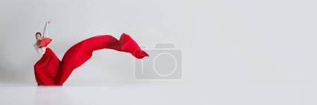 Téléchargez les photos : Capturer l'esprit du flamenco. Femme danseuse avec jupe rouge dramatique et fan montrant passion et dramatique. Concept d'art du mouvement, danse classique, beauté. Bannière. Espace vide pour insérer du texte - en image libre de droit