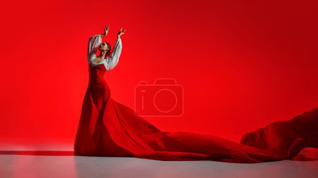 Téléchargez les photos : Intensité de la danse flamenco. Performance artistique créative, danseuse élégante en costume lumineux dansant sur fond rouge. Concept d'art du mouvement, danse classique, beauté, festival - en image libre de droit