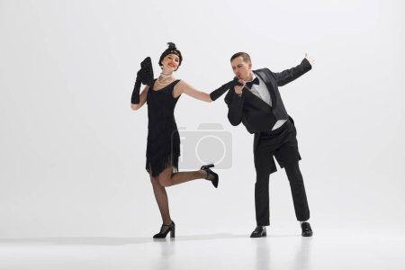Photo for Young couple styled in 1920s fashion, elegant man and woman dancing isolated against white studio background. Concept of art, retro and vintage, hobby, entertainment, 20s - Royalty Free Image