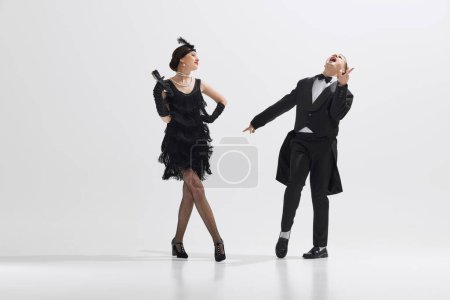 Photo for Dramatic dance performance with emotional and artistic couple, man and woman dressed in 1920s fashion dancing isolated on white studio background. Concept of art, retro and vintage, entertainment, 20s - Royalty Free Image