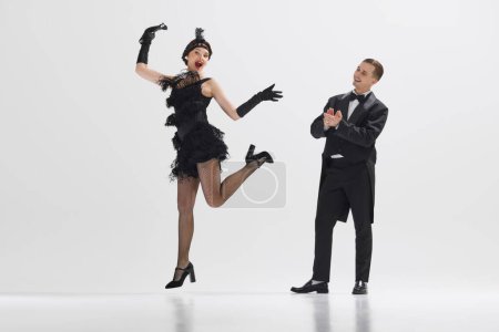 Photo for Handsome man looking at beautiful woman dancing and clapping with admiration isolated over white studio background. Concept of art, retro and vintage, hobby, entertainment, 20s - Royalty Free Image