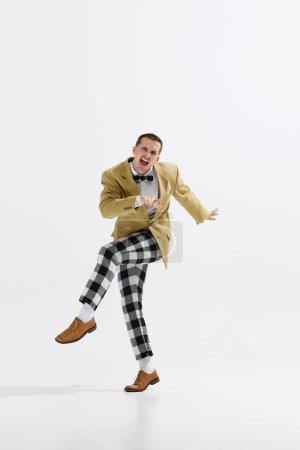 Photo for Lively young male dancer dressed in retro-inspired checkered pants and jacket performing, dancing isolated over white studio background. Concept of art, retro and vintage, hobby, entertainment, 20s - Royalty Free Image