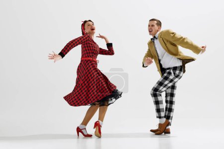 Foto de Vibrante actuación de baile, pareja joven con atuendo apropiado para el período de mediados del siglo XX bailando aislado sobre fondo de estudio blanco. Concepto de arte, retro y vintage, hobby, entretenimiento, 20s - Imagen libre de derechos