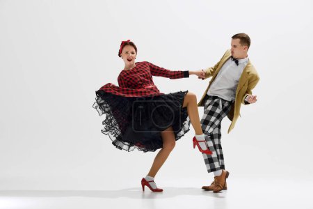 Photo for Stylish and playful couple in 1950s style clothes performing dynamic dance, expressing joy and excitement isolated over white studio background. Concept of art, retro and vintage, entertainment, 20s - Royalty Free Image