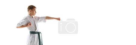 Foto de Estudiante de artes marciales enfocado en kimono blanco y entrenamiento de cinturón verde, practicando posturas aisladas sobre fondo de estudio blanco. Concepto de deporte, artes marciales, deporte de combate, estilo de vida saludable y activo - Imagen libre de derechos