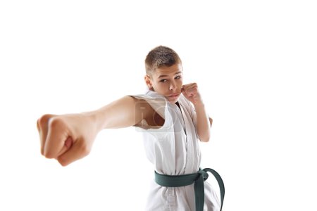 Foto de Patada Taekwondo realizada por determinado joven atleta de karate en kimono blanco y cinturón verde aislado sobre fondo blanco. Concepto de deporte, artes marciales, deporte de combate, estilo de vida saludable y activo - Imagen libre de derechos