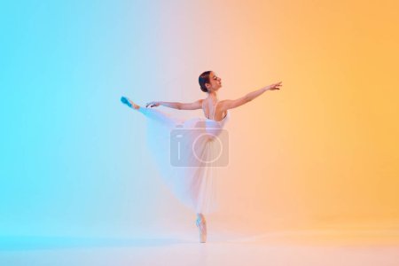 Photo for Elegant ballet dancer in white ensemble gracefully extends in neon light against blue-orange gradient background. Concept of art, movement, classical and modern fusion, beauty and fashion. Ad - Royalty Free Image