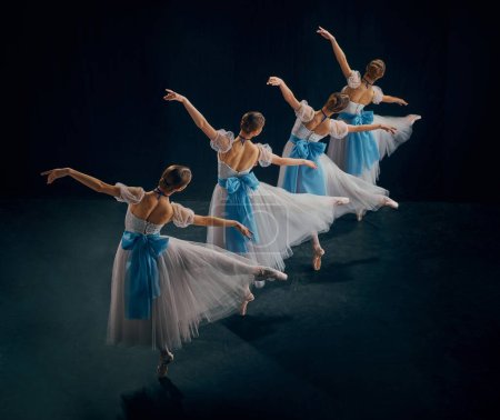 Photo for Four ballerinas in beautifully choreographed pose, their white tutus with blue bows gracefully flowing. Concept of beauty, classic and modernity, contemporary art, movement. Ad - Royalty Free Image