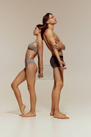 Photo for Full-length image of young beautiful girl and handsome man, models with athletic fit bodies posing in underwear on grey studio background. Concept of beauty, body, sport and health, fashion - Royalty Free Image