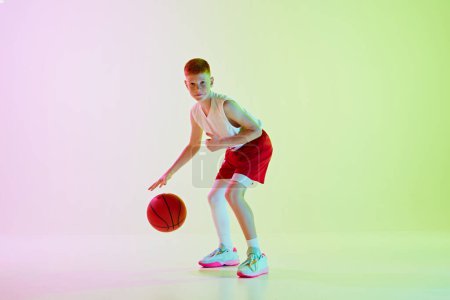 Photo for Focused boy, basketball player training, playing, dribbling ball against gradient background in neon light. Little winner. Concept of sport, childhood, sport school, active lifestyle - Royalty Free Image