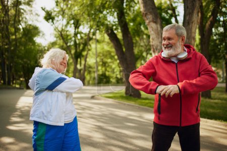 Photo for Cheerful elderly couple, man and woman in sportswear training ion early morning in public park, showing vitality and happiness. Concept of sport, aging, active and healthy lifestyle, health care - Royalty Free Image