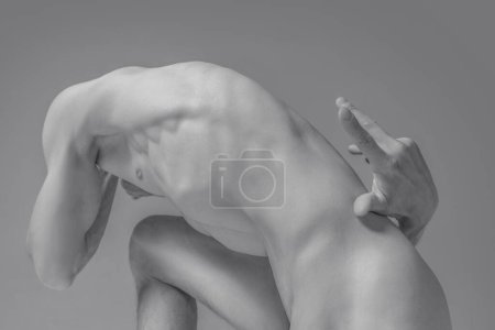 Human form in dynamic pose emphasizing motion and strength. Monochrome photography highlighting muscles and curves of defined male body. Concept of body aesthetics, nature and beauty of human.