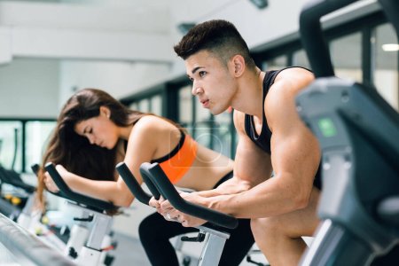 Photo for A young couple on cycling machine working out together - Royalty Free Image