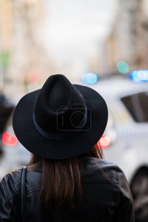 Foto de Retrato retrovisor de una joven mujer caucásica con sombrero en medio de la ciudad - Imagen libre de derechos