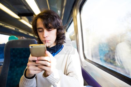 Foto de Joven adolescente pequeño usando el teléfono celular mientras está sentado en un tren . - Imagen libre de derechos