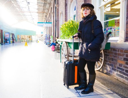 Foto de Mujer adulta arrastrando maleta a través de una estación de tren. - Imagen libre de derechos