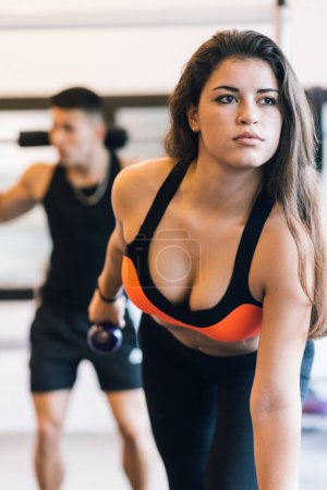 Foto de Pareja joven haciendo ejercicio juntos solos en el gimnasio levantamiento de pesas. - Imagen libre de derechos