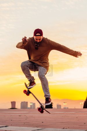 Foto de Chico saltando en el aire con su monopatín con increíble puesta de sol en el fondo. - Imagen libre de derechos