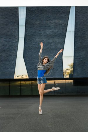 Foto de Mujer en ropa de calle y zapatos de bailarina bailando al aire libre sobre hormigón. - Imagen libre de derechos