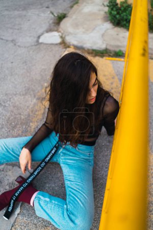 Foto de Alto ángulo de tiro de un joven modelo posando para la cámara sentado en el suelo de las calles - Imagen libre de derechos
