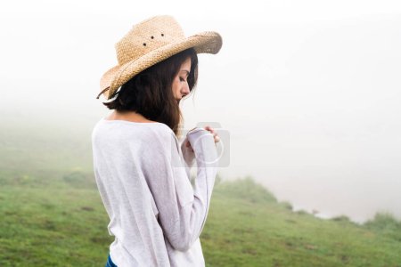 Foto de Retrato de una mujer caucásica con un sombrero de paja mirando hacia otro lado de la cámara sobre un fondo nebuloso. - Imagen libre de derechos