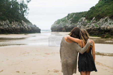 Téléchargez les photos : Deux femmes s'embrassant marchant sur la plage - en image libre de droit
