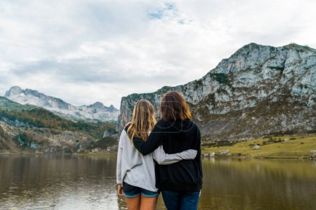 Foto de Foto retrospectiva de dos niñas mirando un paisaje de un lago y altas montañas en Asturias. - Imagen libre de derechos