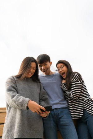 Photo for Three Chinese people in casual clothing taking selfie and making faces. - Royalty Free Image