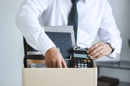 personnel packing personal belongings and files into a brown cardboard box with resignation letter for changing and resign from work concept for quit or change of job