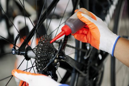 Foto de Close - up of the male mechanic working in the bicycle repair shop, mechanic repairing bike using a special tool, wearing protective gloves. Bike Maintenance Concept. - Imagen libre de derechos