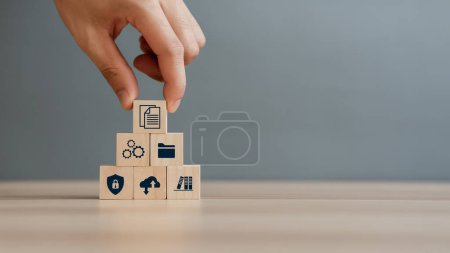 Foto de Hand putting document icon in the wooden cube for document management digital file data online records keeping, database technology, file access, and doc sharing. - Imagen libre de derechos