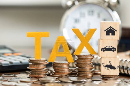 Photo for Tax Concept. Word tax put and icon house, land, car on stacked coins with coins inside and clock on the wooden table. Tax time - Royalty Free Image