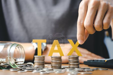 Steuerkonzept: Wortsteuer und gestapelte Münzen auf den Schreibtisch