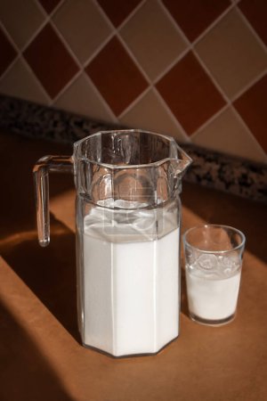 Téléchargez les photos : Une cruche en verre avec des supports de lait sur une table en bois - en image libre de droit