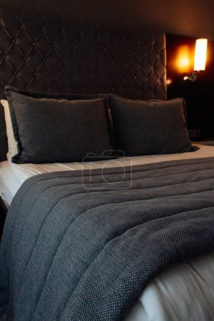 Téléchargez les photos : Lit fait dans la chambre à coucher dans des couleurs grises avec couverture lourde - en image libre de droit