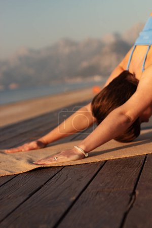 the girl on the background of the sea is doing classical yoga