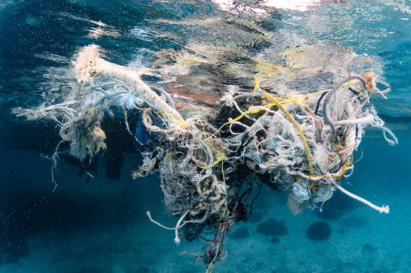 Abandoned debris fishing net or ghost net and plastic garbages in the sea. Clean up the ocean by collecting waste. Save the ocean and underwater world from trash pollution. Environmental conservation