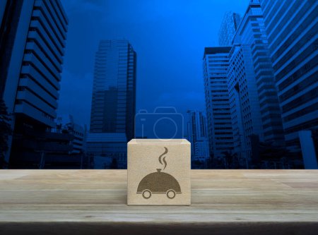 Téléchargez les photos : Icône cloche restaurant sur cube bloc de bois sur table en bois sur tour de bureau moderne et gratte-ciel, concept de livraison de nourriture d'affaires en ligne - en image libre de droit