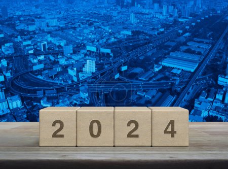 Photo for 2024 letter on wood block cubes on wooden table over modern city tower, street, expressway and skyscraper, Happy new year 2024 cover concept - Royalty Free Image