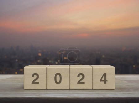 Photo for 2024 letter on wood block cubes on wooden table over blur of cityscape on warm light sundown, Happy new year 2024 cover concept - Royalty Free Image