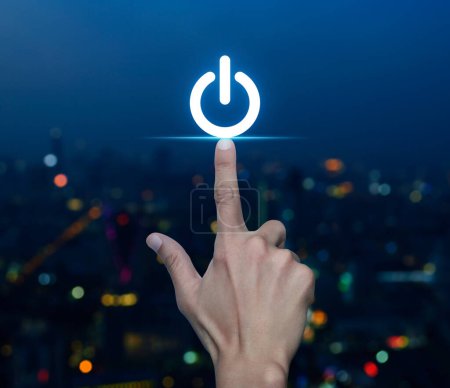 Photo for Hand pressing power button icon over blur colorful night light modern city tower and skyscraper, Start up business concept - Royalty Free Image