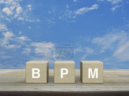 BPM Akronym auf Holzblockwürfeln auf Holztisch über blauem Himmel mit weißen Wolken, Geschäftsprozessmanagement-Konzept