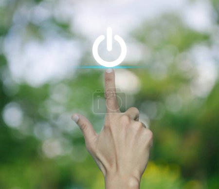 Téléchargez les photos : Main appuyant sur l'icône bouton d'alimentation sur flou arbre vert dans le parc, Démarrer concept d'entreprise - en image libre de droit